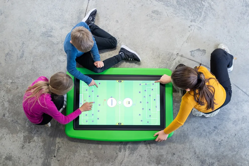 Kinderen rond een Wecoplay educatieve oplossing met touchscreen.